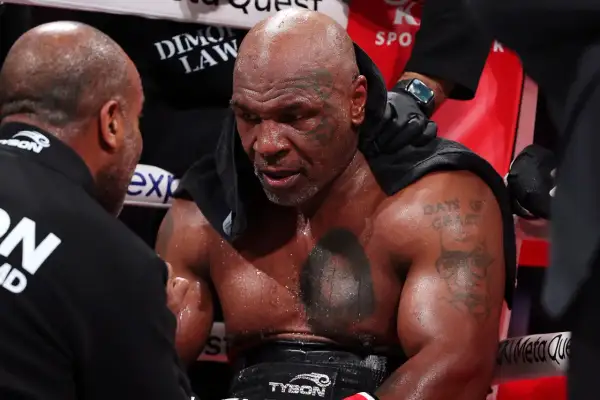 Mike Tyson, sweaty and focused, receives advice from his corner. His "Mike Tyson schedule" is etched in his determined expression.