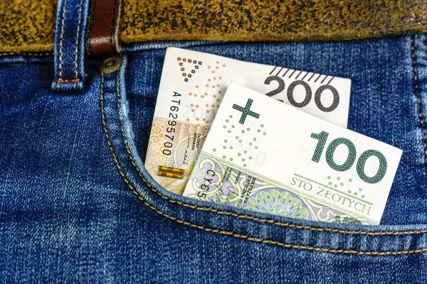 Polskie banknoty 100 i 200 zł w kieszeni dżinsów.