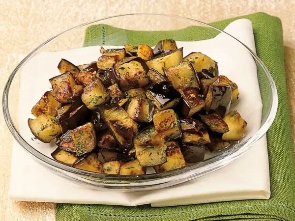 Melanzane a funghetto ricetta della nonna: cubetti dorati e saporiti, conditi con erbe aromatiche, pronti per essere gustati.