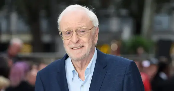 Uśmiechnięty Michael Caine w okularach, ikona kina. Jego niezapomniane role w licznych filmach na zawsze zapisały się w historii.