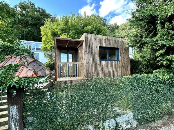 Une charmante tiny house en bois, nichée dans un jardin verdoyant, évoque un coin de nature paisible près de Paris.