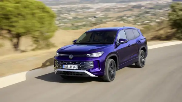 Fioletowy VW Tayron jedzie po krętej drodze wśród wzgórz.