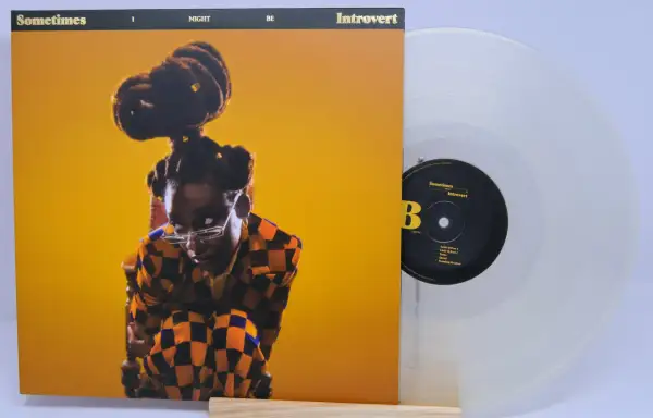 Little Simz, czasem introvert, na okładce płyty "Sometimes I Might Be Introvert". Obok przezroczysta winylowa płyta.