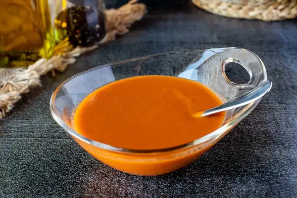 Un cuenco de cristal con una deliciosa salsa americana anaranjada, lista para acompañar tus platos.