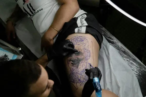 Un tatuador trabaja en un retrato en la pierna de un cliente, demostrando la habilidad de los mejores tatuadores de España.