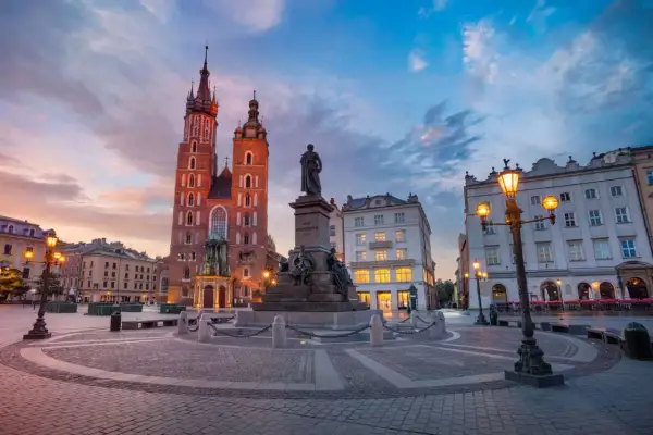 Krakowski rynek główny o zachodzie słońca. Monumentalna Bazylika Mariacka i pomnik Adama Mickiewicza w blasku latarni.
