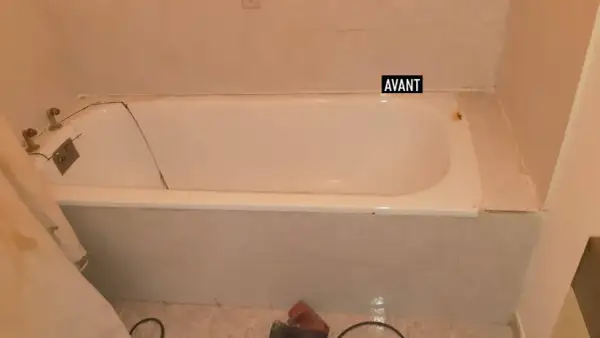 Salle de bain avant rénovation baignoire : baignoire blanche fissurée, robinetterie ancienne, carrelage beige.
