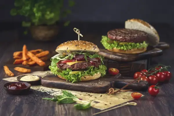 Pyszny hamburger, którego skąd pochodzi, z soczystą wołowiną, warzywami i serem, podany z frytkami i sosami.