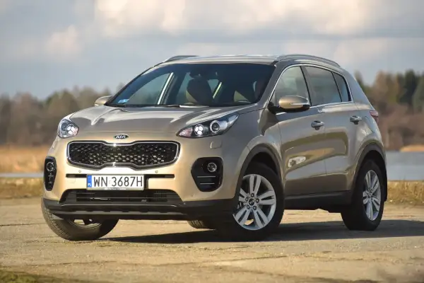 Złoty Kia Sportage na tle jeziora. Sprawdź jego wymiary i możliwości terenowe.