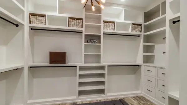 Armario de pladur blanco con cestas, caja de Louis Vuitton y barras para colgar ropa.