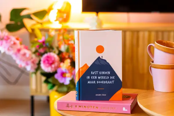 Boek "Rust vinden in een wereld die maar doordraait" op een roze dagboek. Handig voor wie hooggevoelig is en zoekt naar rust.