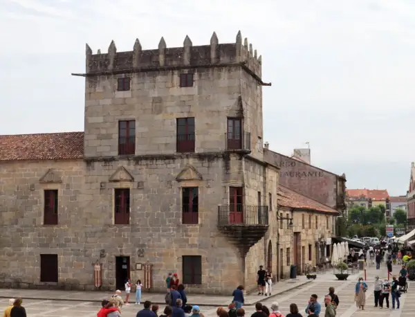Plaza de Cambados que ver: torre medieval de piedra, casas históricas y gente paseando.