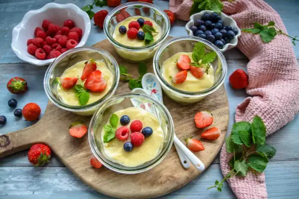 Vier Gläser mit selbstgemachtem Pudding, garniert mit frischen Beeren und Minze. Ein Genuss für Augen und Gaumen!
