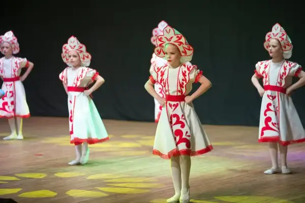 Niñas con trajes tradicionales bailan en un escenario de teatro.