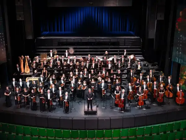 Wielka orkiestra symfoniczna na scenie, muzycy w strojach galowych, dyrygent. To właśnie opera co to za widowisko!