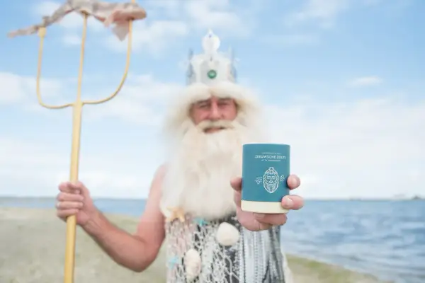 Neptunus, god van de zee, toont trots een potje Zeeuwse zoute met een vis aan zijn drietand.