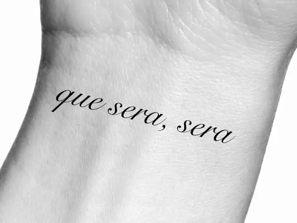 Tatuaż na nadgarstku z napisem "que sera, sera", co oznacza "co ma być, będzie".