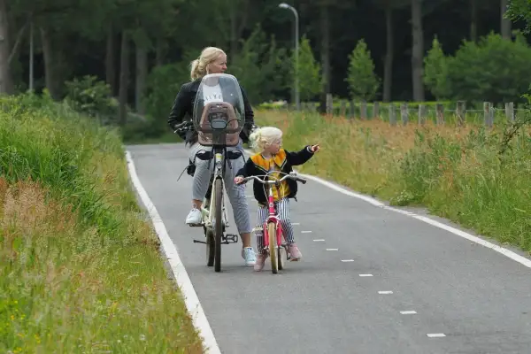 Mama i córka na rowerach odkrywają rodzinne trasy rowerowe. Dziecko wskazuje drogę.