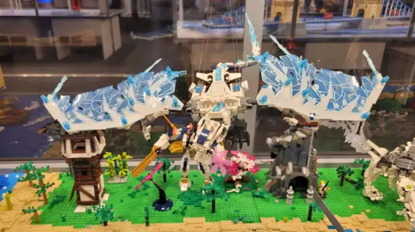 Lodowy smok w muzeum LEGO w Warszawie walczy z robotem na tle miniaturowej wioski.