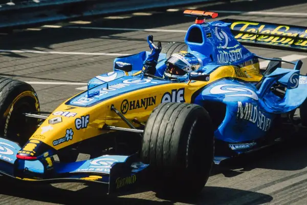 Un coche de Renault F1 azul y amarillo, con el piloto saludando.