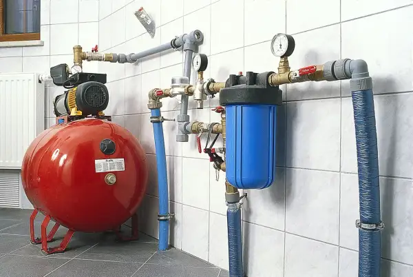System hydroforowy: czerwony zbiornik, pompa, niebieski filtr wody i manometry. To rozwiązanie zapewnia stałe ciśnienie wody.