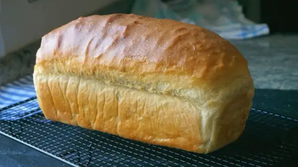 Pan de molde dorado y esponjoso enfriándose en una rejilla, perfecto para tus próximas recetas con pan de molde.