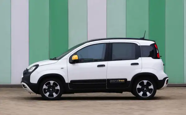 Biały fiat pandina z żółtymi lusterkami stoi na tle zielono-białej ściany.