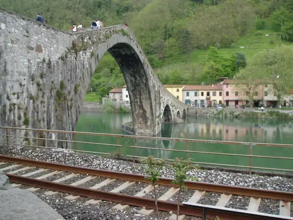 Ponte del Diavolo a Borgo a Mozzano, con case colorate e un fiume verde.