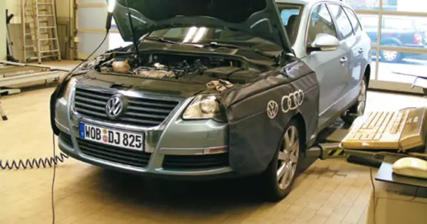 Passat B6 2.0 TDI 140KM w warsztacie, z otwartą maską i osłoną na błotniku. Obok klawiatura i myszka.