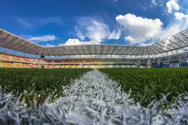Piękny, pusty stadion Podbeskidzie z kolorowymi trybunami i zieloną murawą pod błękitnym niebem.