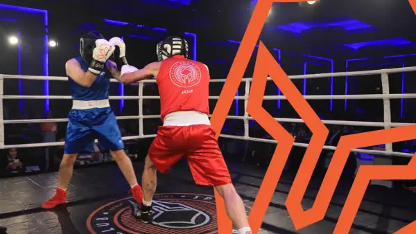 Two boxers in the lightest boxing weight class spar in a ring, one in blue, the other in red.