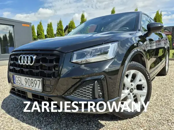 Czarny Audi Q2 na żwirowym podjeździe. Sprawdź atrakcyjną audi q2 cena i zarezerwuj jazdę próbną.