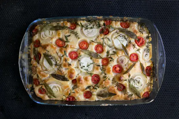 Goldbraune Focaccia mit Kirschtomaten, Zwiebelringen und Kräutern. Ein köstliches Beispiel für Focaccia Rezepte.