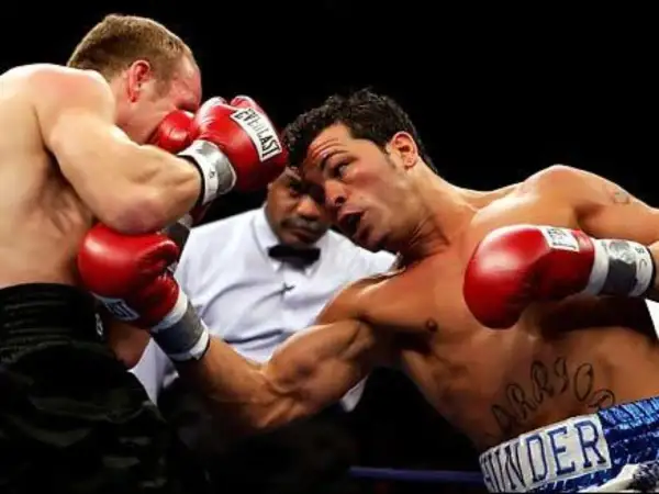 Boxer lands a powerful body shot, his opponent recoils as the referee watches closely.