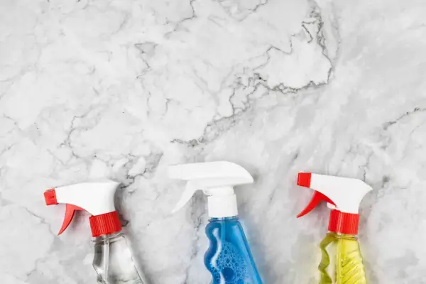 Tre flaconi spray su marmo bianco, pronti per scoprire come pulire il marmo macchiato.