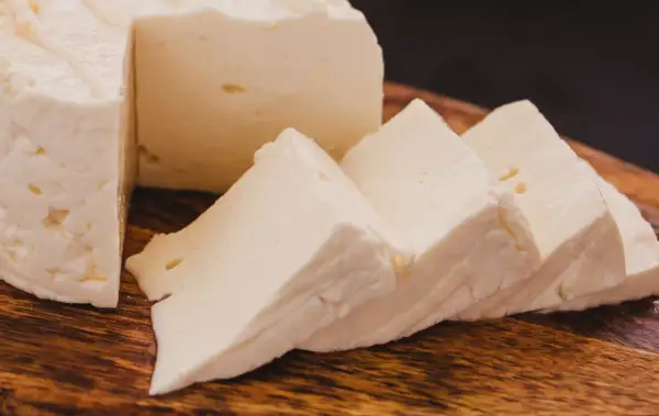Queso de cabra fresco y cortado en cuñas sobre tabla de madera. Ideal para ensaladas, con pocas calorias.