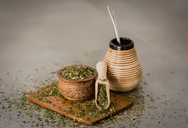 Naczynie z yerba mate i bombilla. Susz rozsypany na desce. Czy yerba mate ma właściwości negatywne?