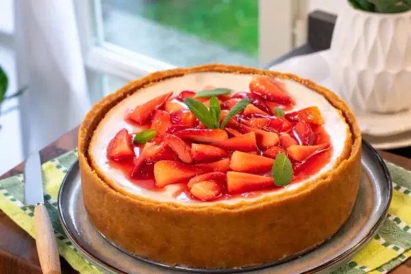 Cheesecake con mascarpone e fragole fresche, guarnita con menta. Un dolce invitante e goloso.