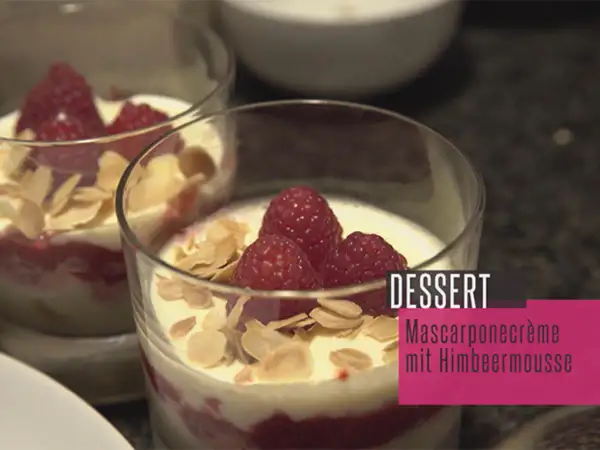 Zwei Gläser mit Himbeer-Mascarpone-Creme, garniert mit frischen Himbeeren und Mandelblättchen. Ein köstliches Dessert.
