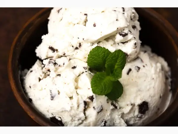 Cremiges Stracciatella Eis mit Schokoladenstückchen in einer Holzschale, garniert mit frischer Minze. Ein einfaches Stracciatella Eis Rezept zum Nachmachen.