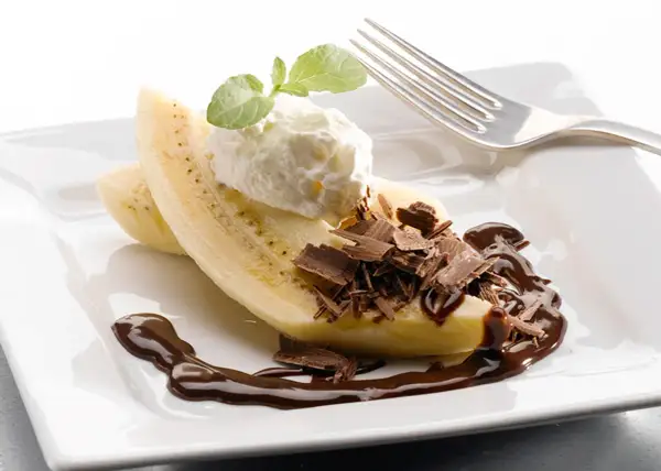 En bananhalva med vispgrädde, chokladspån och chokladsås. En klassisk banana split som ser utsökt ut.
