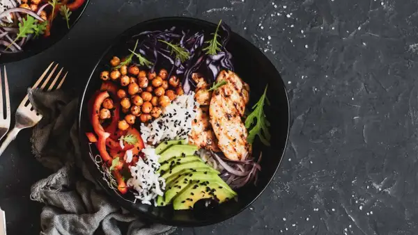 Un bol savoureux avec poulet grillé, riz, pois chiches, avocat et légumes. Parfait pour l'alimentation musculation.