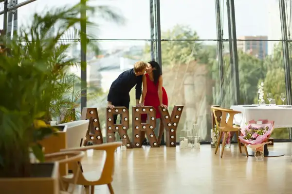 Para zapatrzona w siebie przy literach "MARRY" w nowoczesnym wnętrzu z widokiem na miasto. Idealne miejsce na zaręczyny Polska.
