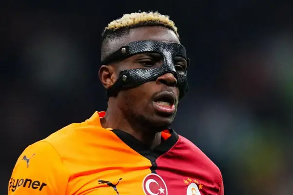 Piłkarz Osimhen w masce ochronnej na twarzy, w pomarańczowo-czerwonej koszulce z herbem Galatasaray.