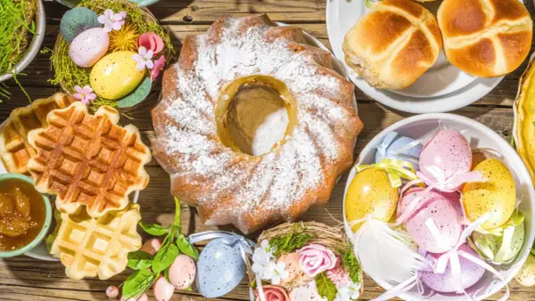 Kiedy jest śniadanie wielkanocne: babka, gofry, jajka w koszyczkach i bułeczki na drewnianym stole.