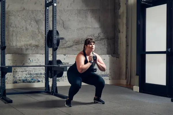 Frau macht einen Goblet Squat mit Kurzhantel als Teil ihres Metcon Workouts.
