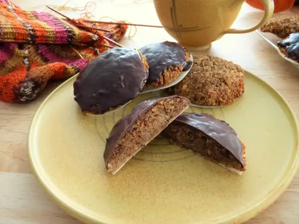 Schokoladen-Lebkuchen, ein köstliches Lebkuchen Rezept ohne Mehl, liegen auf einem Teller neben Strickzeug und einer Tasse.