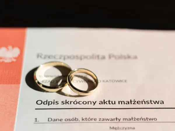 Złote obrączki na odpisie skróconym aktu małżeństwa. Dokument potwierdza zawarcie związku, jak wygląda akt ślubu.