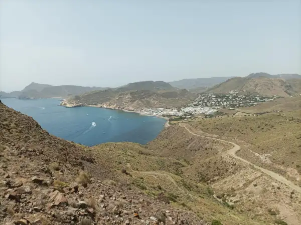 Vista panorámica de la costa de Almería, con el mar azul, un pueblo blanco y el paisaje árido del cerro negro.