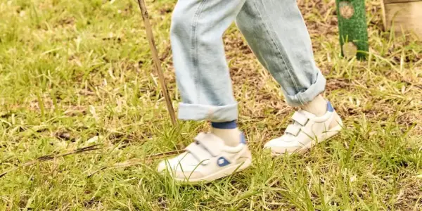 Białe sneakersy na rzepy, idealne na spacer po trawie. To wygodne buty dla aktywnych.